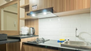 A modern kitchen with wooden cabinets, a black countertop, a stainless steel sink, and a kettle.