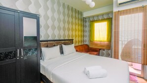 Une chambre d’hôtel équipée d’un lit, d’une armoire, d’une fenêtre avec des rideaux et d’un appareil de climatisation.