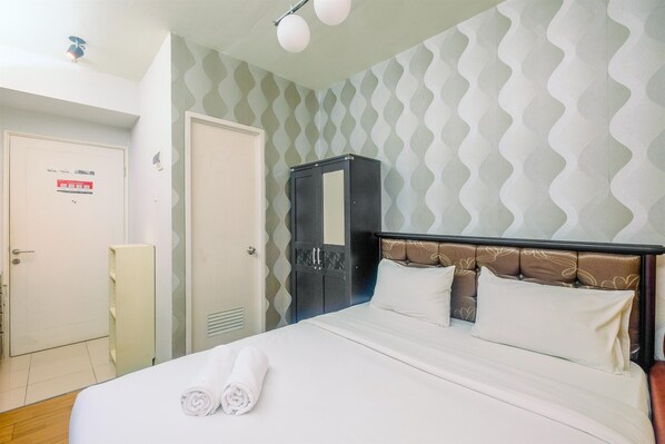 A hotel room with a bed, a wardrobe, and a door. - Comfy and Minimalist Studio at Pakubuwono Terrace Apartment (Jakarta)