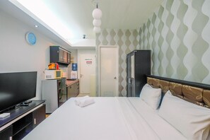 A hotel room with a bed, a TV, a microwave, and a wardrobe. - Comfy and Minimalist Studio at Pakubuwono Terrace Apartment (Jakarta)