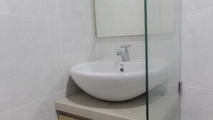A bathroom with a white sink, a mirror, and a glass shower enclosure.