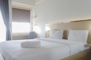 Quarto de hotel com uma cama grande, uma mesa de cabeceira, uma cadeira e uma janela com cortinas.