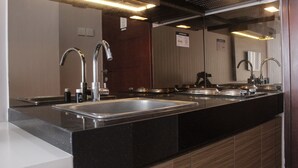 Eine moderne Küche mit einem großen Edelstahlspülbecken, einem Zweifacharmaturen-Wasserhahn und einem eingebauten Kochfeld.