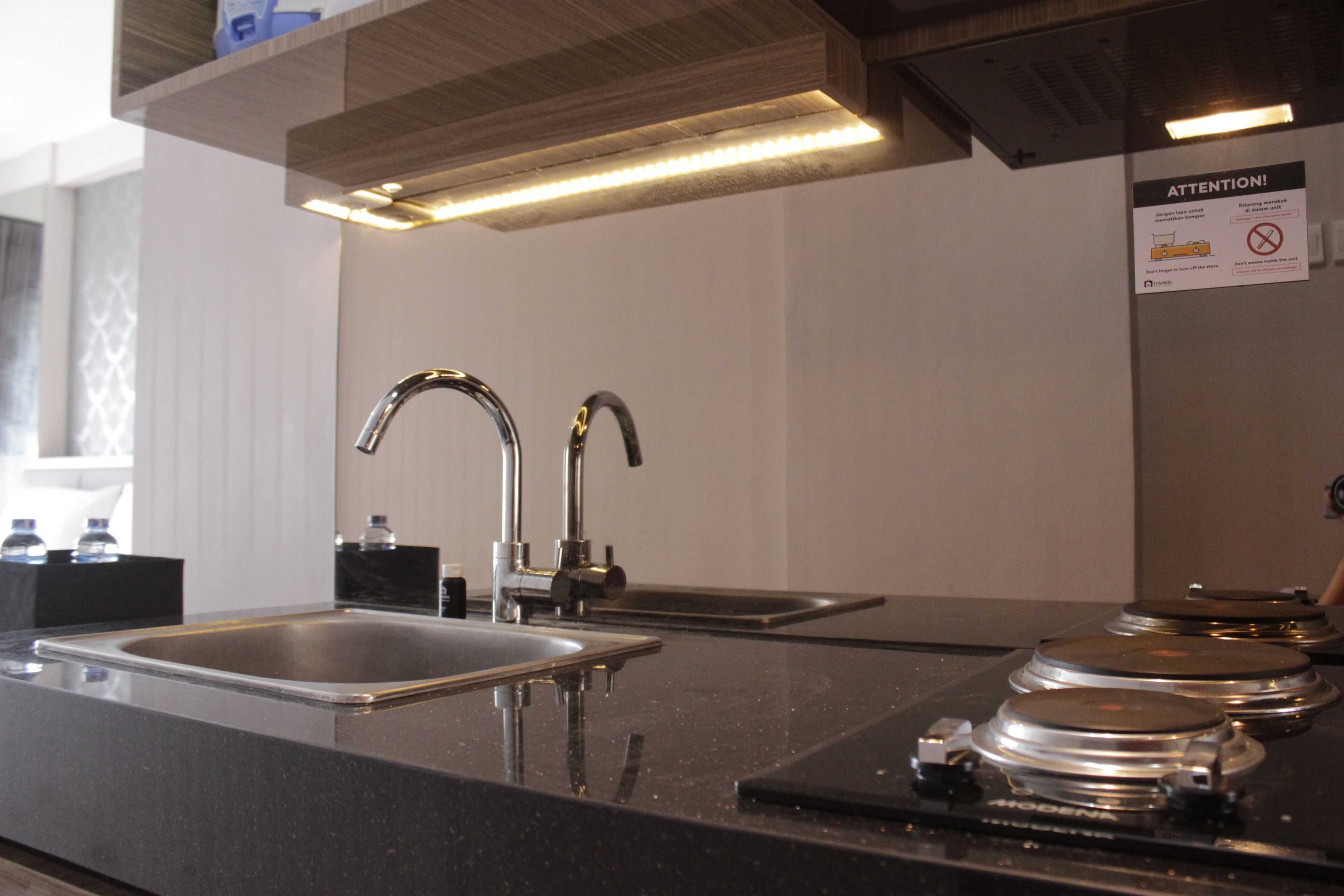 A modern kitchen with a stainless steel sink, a double faucet, and a built-in coffee machine.