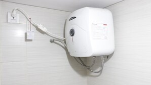 Ein an der Wand befestigter Warmwasserbereiter mit Einstellknopf und Etikett.