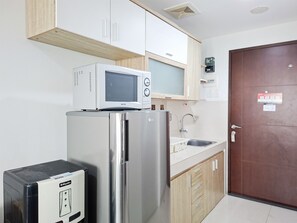 A compact kitchen with a microwave, refrigerator, and a small appliance unit.