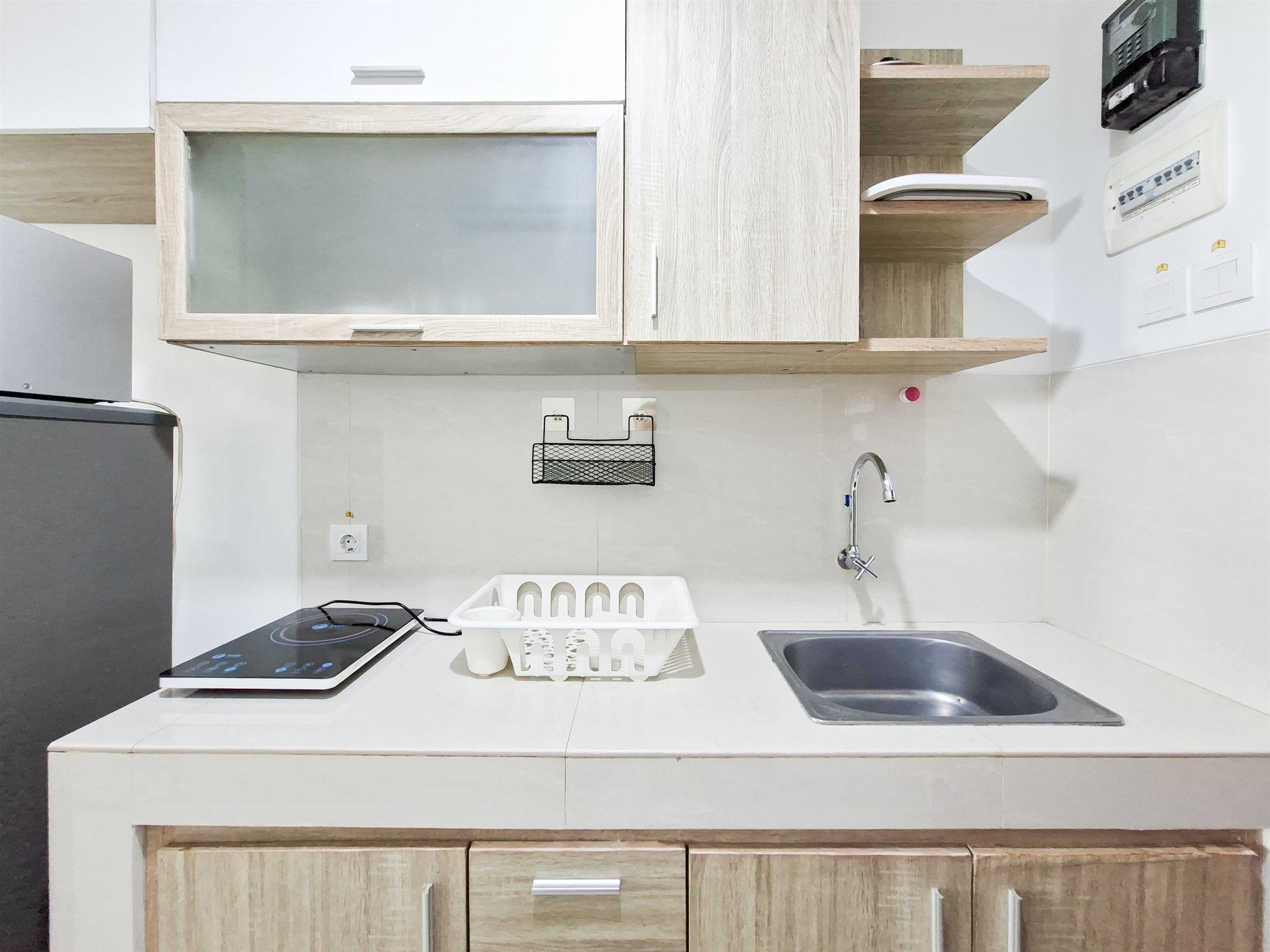 A kitchen with a refrigerator, a sink, a stove, and wooden cabinets.
