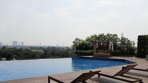 A swimming pool with lounge chairs and a garden area. - Bright Studio Apartment at Springwood Residence (Tangerang)