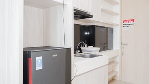 Una cocina compacta con un refrigerador negro, un lavamanos y un microondas.