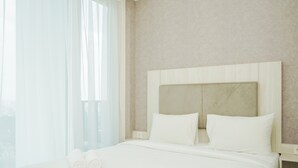 Una habitación de hotel con una cama grande, dos almohadas y un edredón impecable.