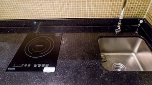 A kitchen with a black induction cooktop and a stainless steel sink. - Best Studio Benson Apartment Connected to Pakuwon Mall next to Anderson (Surabaya)