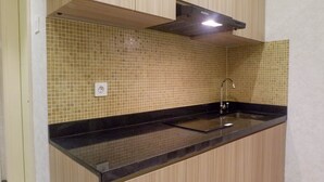 A kitchen with a black countertop, a sink, and a tiled backsplash. - Best Studio Benson Apartment Connected to Pakuwon Mall next to Anderson (Surabaya)