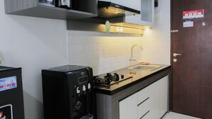 Pieni, käytännöllinen keittiö, jossa on kahvinkeitin, liesi ja pesuallas.