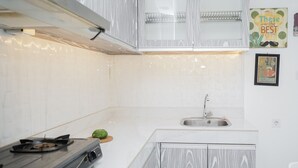 A kitchen with white marble countertops, a gas stove, a sink, and a decorative sign on the wall.