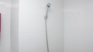 A shower with a handheld showerhead in a tiled bathroom.