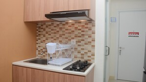 A compact kitchen with a built-in stove, a stainless steel sink, and a white dish rack.