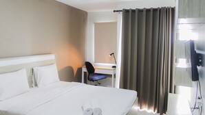 A hotel room with a bed, a desk, a chair, and a TV. - Fully Furnished with Cozy Design Studio Apartment Springwood Residence (Tangerang)