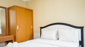 A hotel room with a bed, a wooden wardrobe, and a mirror. - Fully Furnished 2BR Apartment at Great Western Resort (Tangerang)