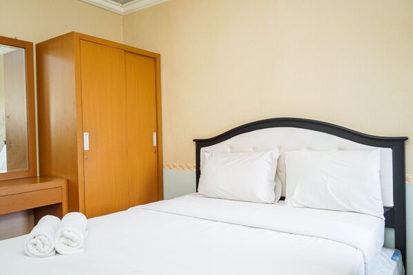 A hotel room with a bed, a wooden wardrobe, and a mirror.