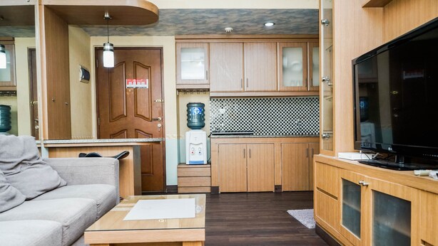 A compact living space with a kitchenette, a sofa, a coffee table, and a television. - Fully Furnished 2BR Apartment at Great Western Resort (Tangerang)