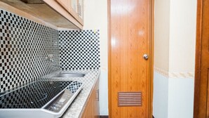 A kitchen with a checkered backsplash, a stove, and a wooden door. - Fully Furnished 2BR Apartment at Great Western Resort (Tangerang)