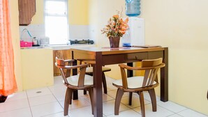 A dining area with a wooden table and chairs, a water dispenser, and a potted plant. - Comfy and Cozy 2BR Great Western Resort Apartment (Tangerang)