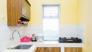A kitchen with a sink, a kettle, a rice cooker, and a gas stove. - Comfy and Cozy 2BR Great Western Resort Apartment (Tangerang)