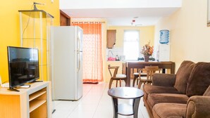 A living room with a TV, sofa, and a dining area with chairs and a table. - Comfy and Cozy 2BR Great Western Resort Apartment (Tangerang)