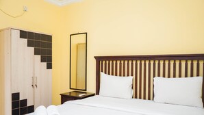 A hotel room with a bed, a wooden wardrobe, a nightstand, and a mirror. - Comfy and Cozy 2BR Great Western Resort Apartment (Tangerang)