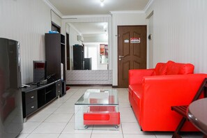 Ein Wohnzimmer mit Glastisch, rotem Sofa, Fernseher und schwarzem Unterhaltungsschrank.