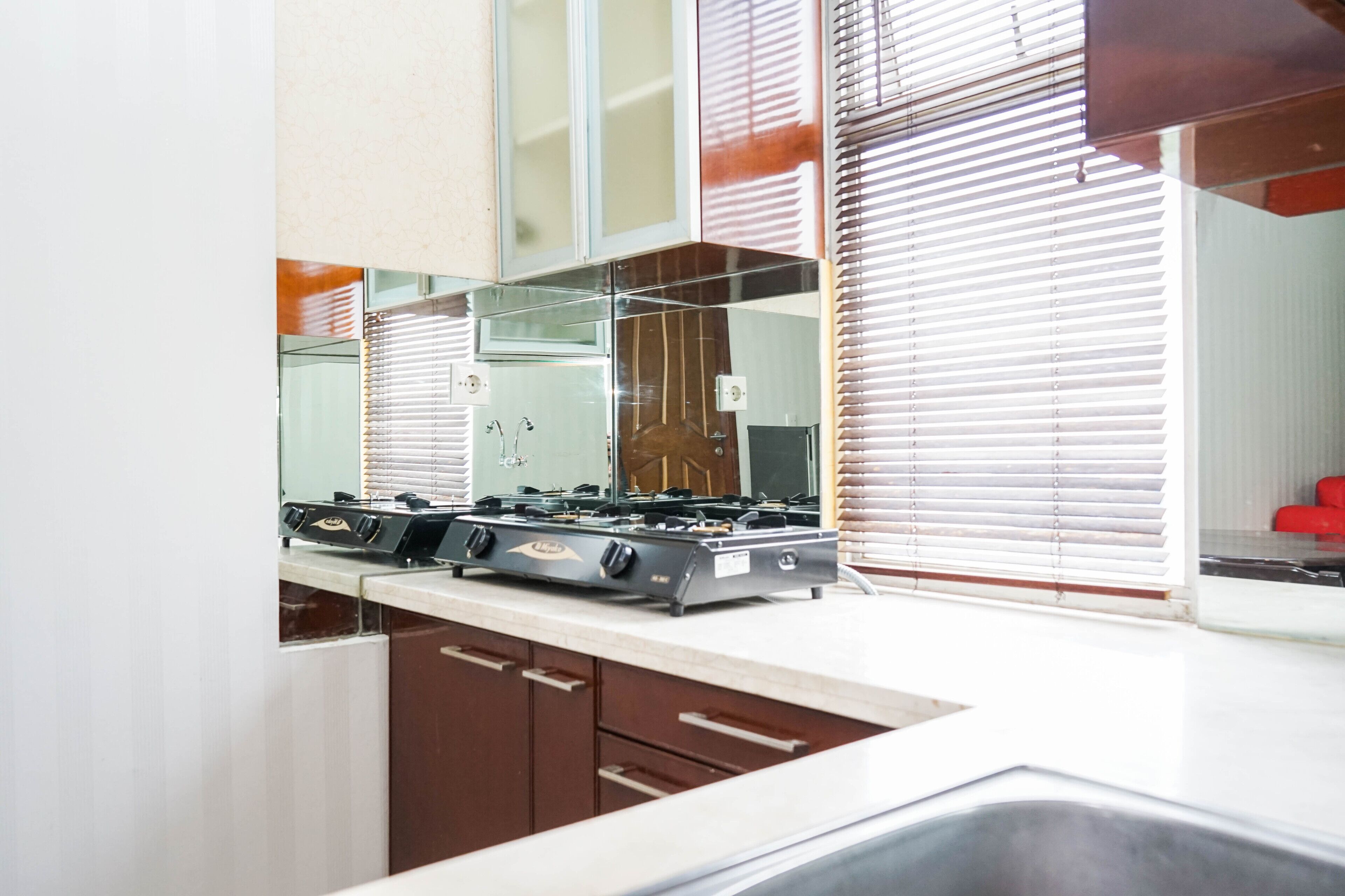 A kitchen with a gas stove, cabinets, and a window with blinds.