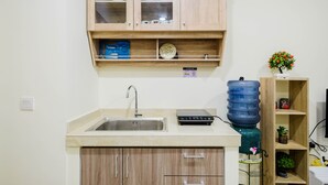 A kitchen with a sink, wooden cabinets, and a water dispenser. - New Furnished and Comfy 2BR at Meikarta Apartment (Cikarang)
