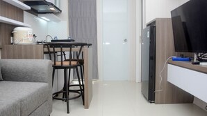 Eine kompakte Küche mit Essbereich, einer Couch, einem Fernseher und einem Kühlschrank.