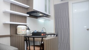 Eine kompakte Küchenzeile mit Kaffeemaschine, Wasserkocher und kleinem Kühlschrank.