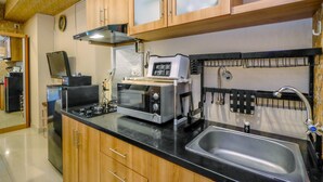 Eine Küche mit Holzausstattung, einer schwarzen Arbeitsplatte, einer Spüle aus Edelstahl, einem Toaster, einer Mikrowelle und einem Herd.