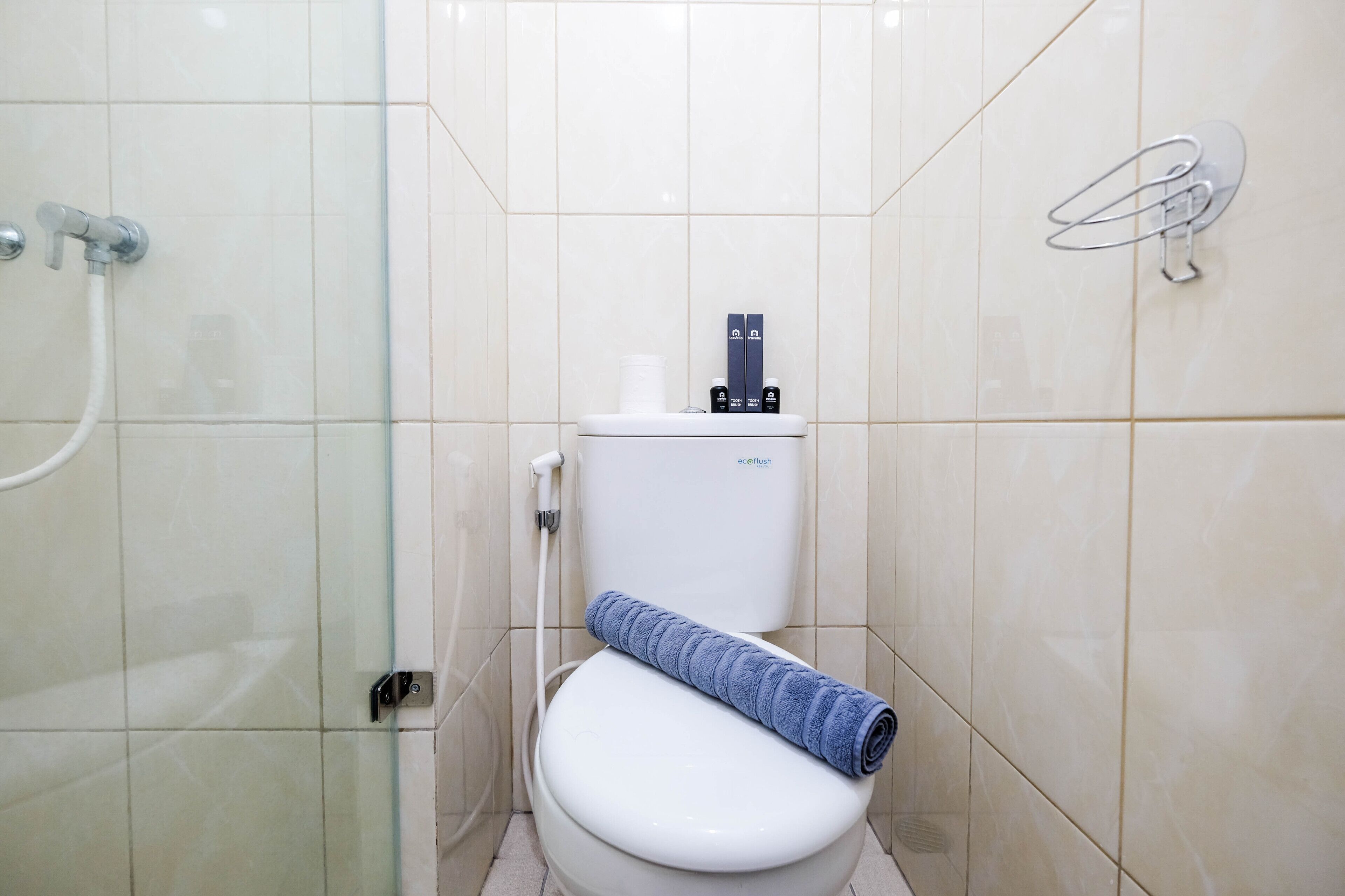 A bathroom with a white toilet, a glass shower enclosure, and a paper towel holder on the wall.