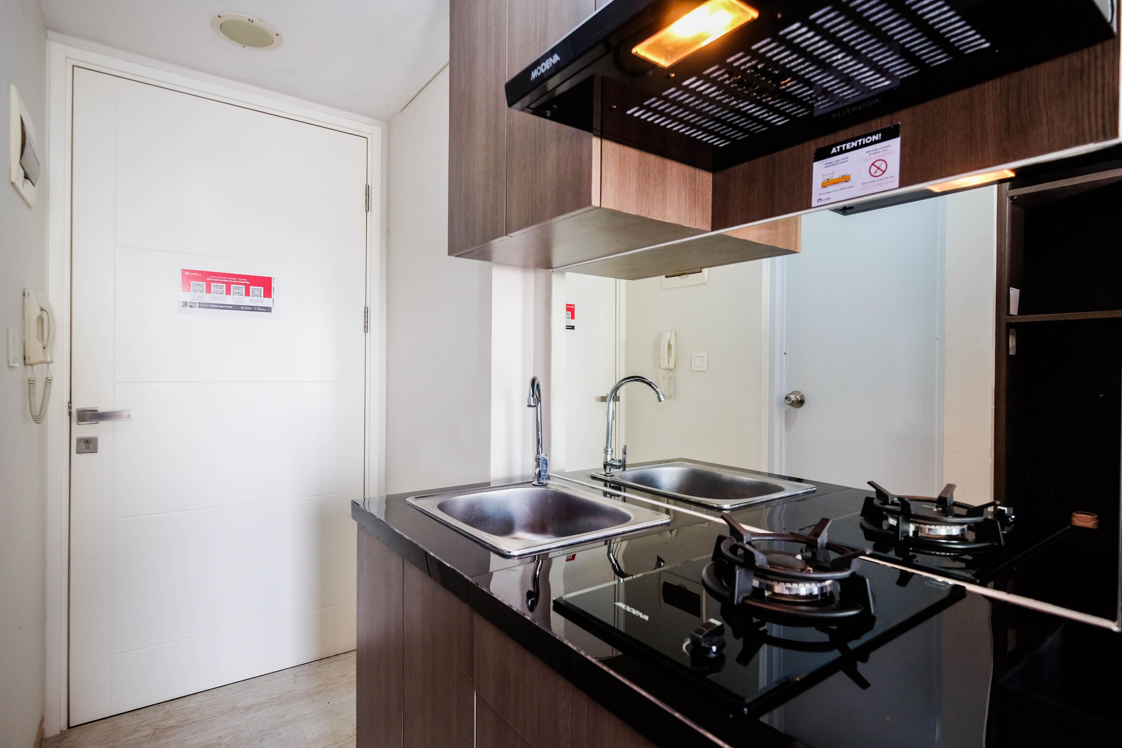 A modern kitchen with two stainless steel sinks, a black countertop, and a gas stove.