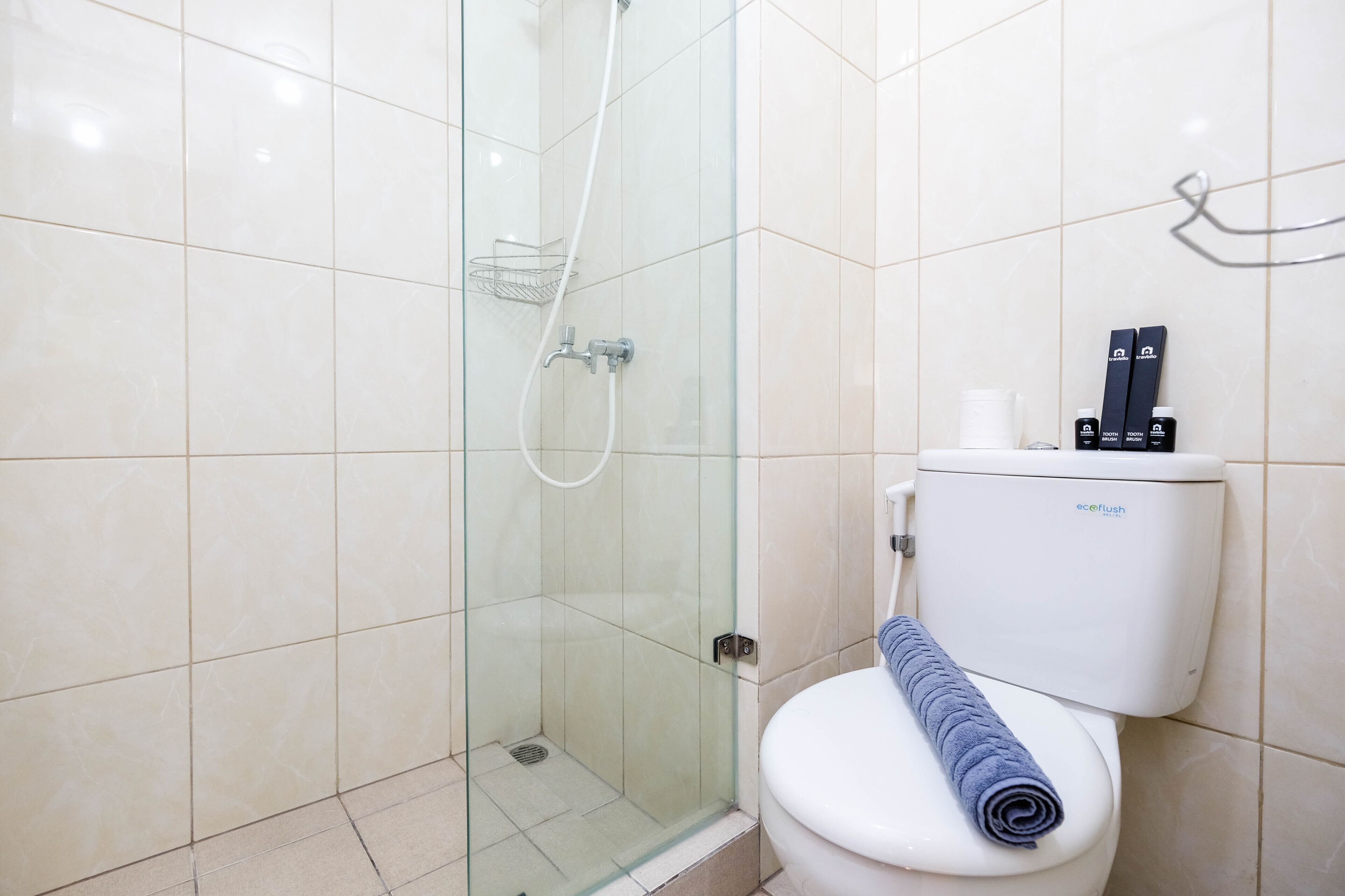 A bathroom with a glass-enclosed shower, a white toilet, and a towel on the seat.