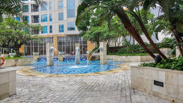 Ein Pool mit Wasserspielen, umgeben von Grünflächen und moderner Architektur.