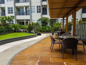 Relax in a shaded seating area under a pergola, surrounded by lush greenery and beautifully manicured lawns.