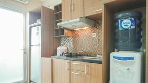 Une cuisine avec des meubles en bois, un réfrigérateur, un distributeur d’eau et un dosseret carrelé.