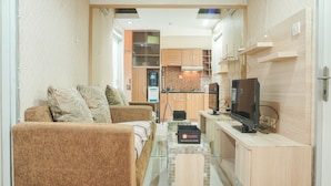 Un espace de vie compact comprenant un canapé, un petit téléviseur et une kitchenette.