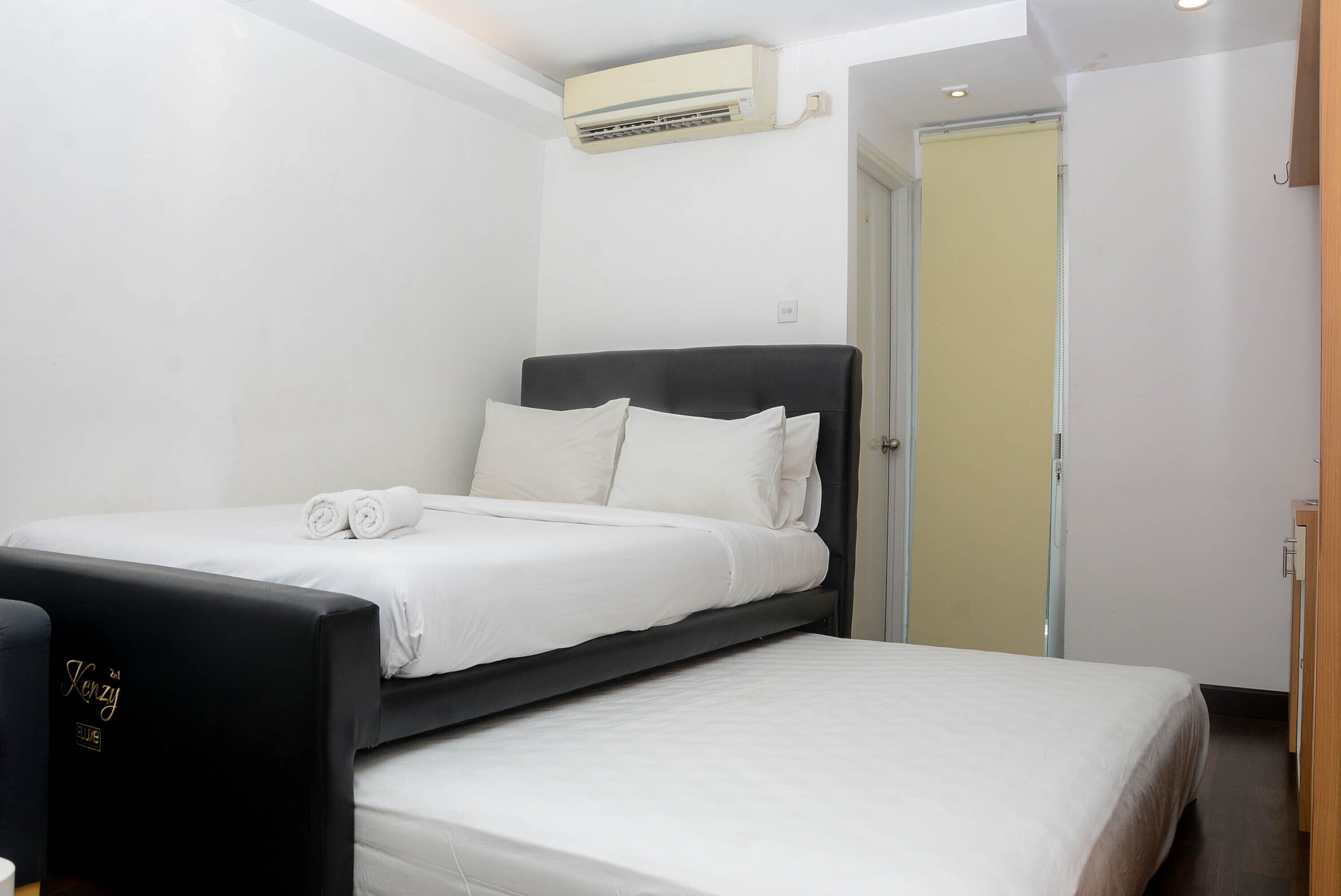 A neatly made bed with white linens and a black headboard in a hotel room.