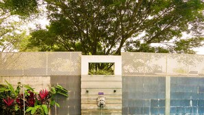 Una piscina con borde de azulejos, una escalera de metal y un muro de piedra con una fuente de agua.