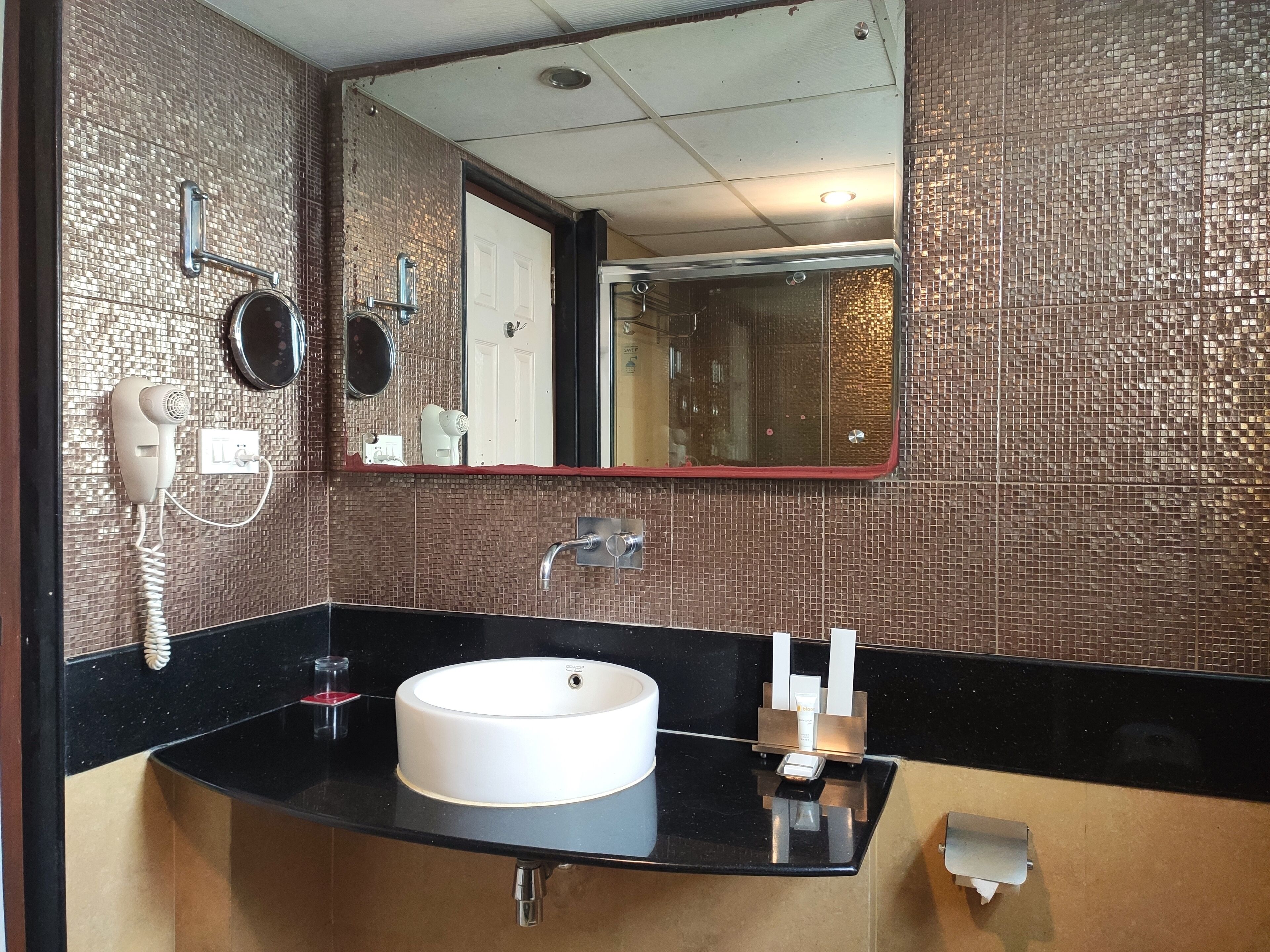 A bathroom with a black countertop, a white sink, and a mirror.