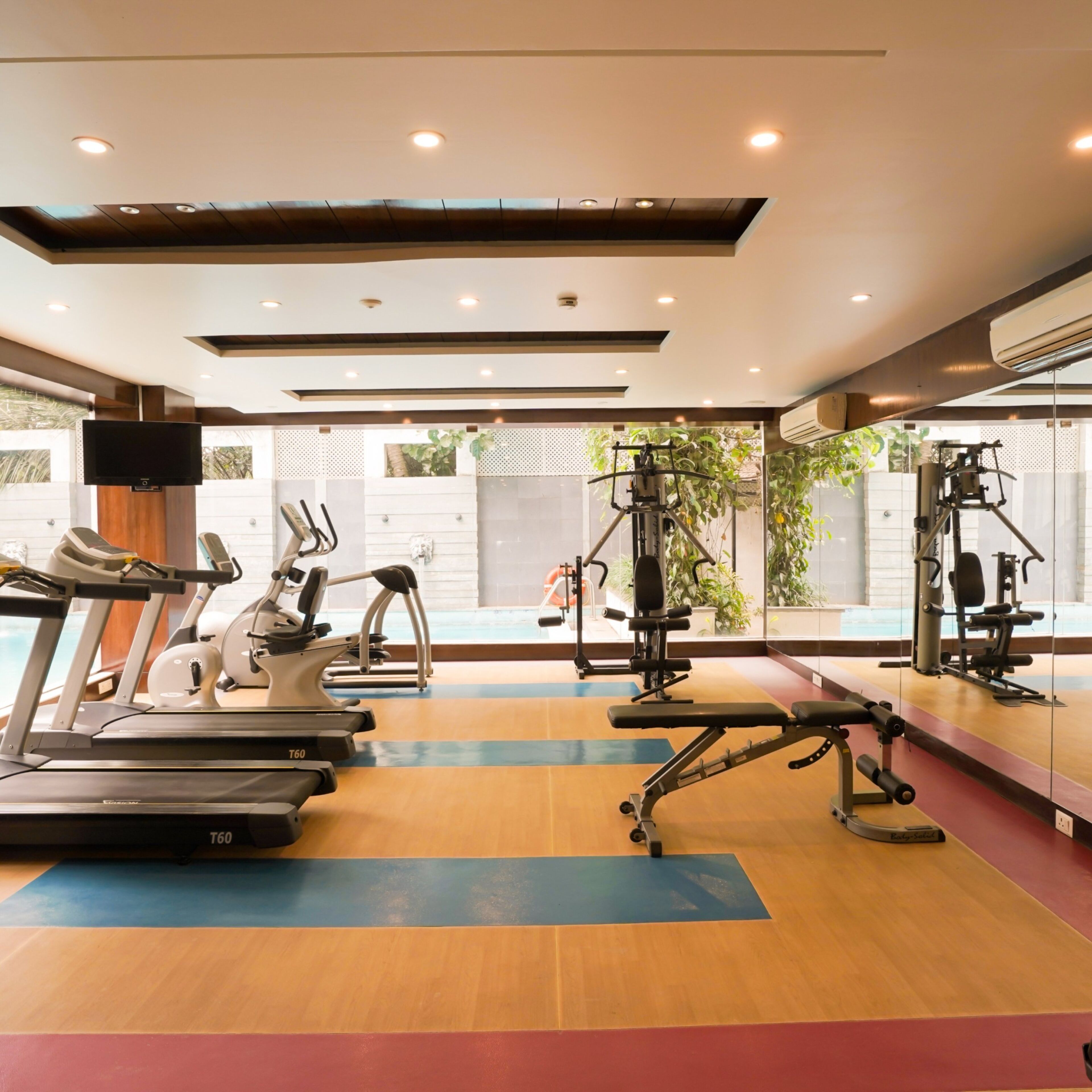 A gym with treadmills, weight machines, and a mirror wall.
