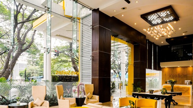 Un moderno vestíbulo de hotel con paredes de vidrio, asientos amarillos y una recepción.