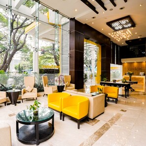 A modern hotel lobby with glass walls, yellow seating, and a reception desk. - bloomSuites  Electronic city (Bengaluru)