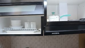 A kitchen with a stainless steel range hood and a white cabinet with a patterned backsplash. - Comfort and Spacious Studio Room Bassura City Apartment (Jakarta)