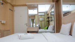 A hotel room with a bed, a bathroom, and a mirror reflecting the room. - Comfort and Spacious Studio Room Bassura City Apartment (Jakarta)